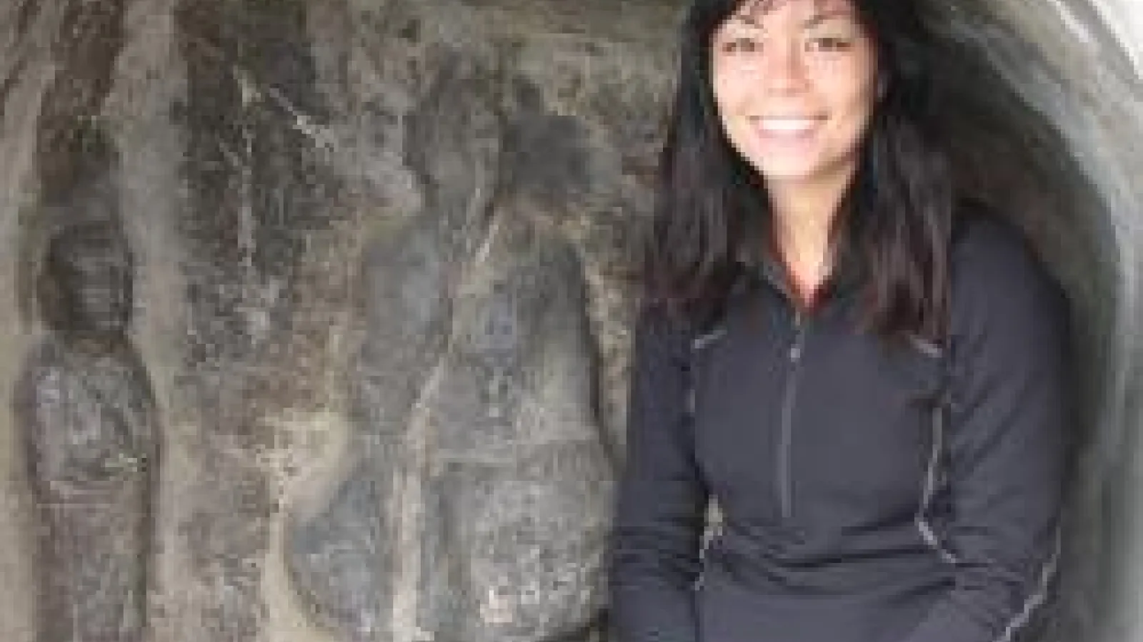 Namiko Kunimoto, a woman sitting on a rock looking at the camera